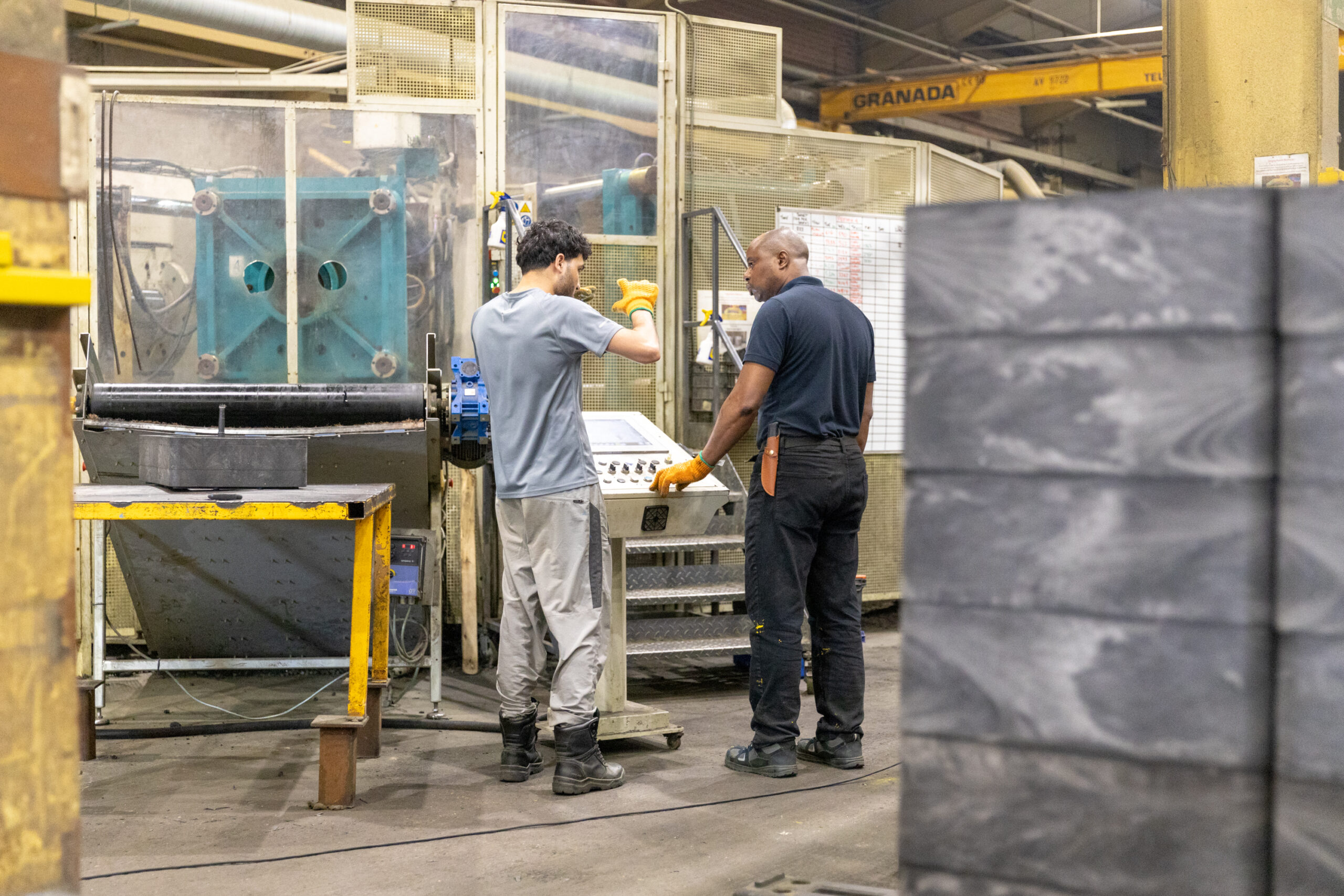 Operatives using injection moulding machinery at Heyside Group, with access chambers to the side